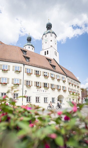 Zwei Radfahrer fahren am Verwaltungsgebäude mit ihrem Fahrrad vorbei.