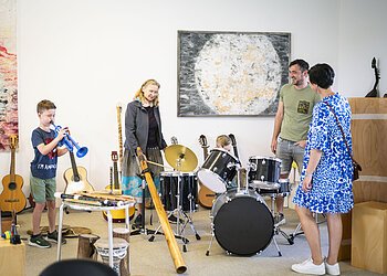 Eine Familie testet während einer Führung im KunstMuseum die Musikinstrumente.