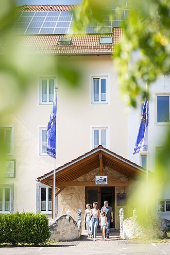 Eingang Seebauer Hotel Gut Wildbad Eine Familie läuft auf dem Hoteleingang Gut Wildbad heraus.
