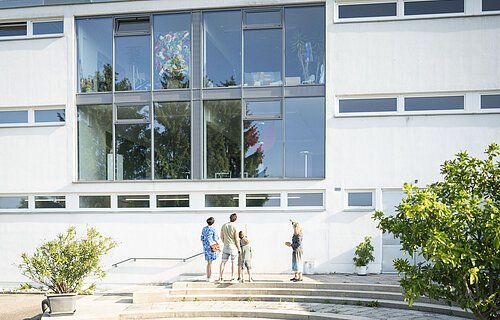 Die Leiterin des KunstMuseums zeigt das Museum von außen und führt es einer Gruppe vor.