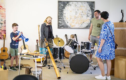 Eine Familie testet während einer Führung im KunstMuseum die Musikinstrumente.