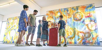 Eine Familie sieht sich im KunstMuseum ein Kunstwerk an.