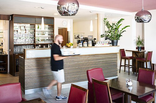 Ein Mann läuft zu den Tischen im Lieblingsgrieche und bedient die Gäste.