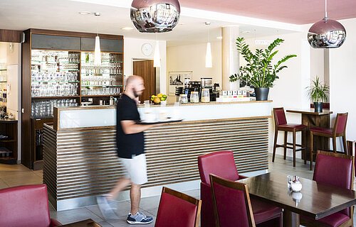 Ein Mann läuft zu den Tischen im Lieblingsgrieche und bedient die Gäste.