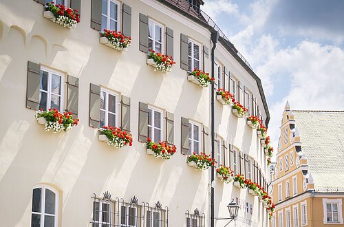 Das Verwaltungsgebäude von außen im Sommer mit Blumenkästen an den Fenstern.