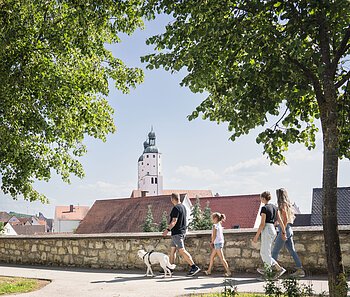 Eine Familie mit Hund geht entlang der Stadtmauer spazieren.