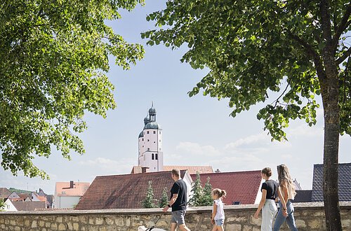Eine Familie mit Hund geht entlang der Stadtmauer spazieren.