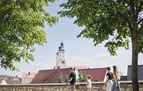Eine Familie mit Hund geht entlang der Stadtmauer spazieren.